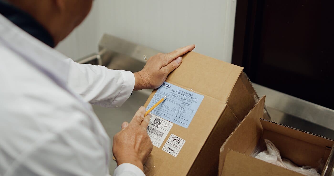 Quality inspector in a white coat scanning a labelled box